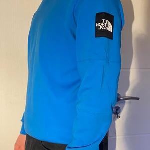 Blå North Face sweatshirt - Blå sweatshirt från North Face i storlek M. Jag är en storlek L så därför sitter den lite tight på mig. Köptes för ca 800 kr. Har använts ett fåtal gånger, är i utmärkt skick. Köpes direkt för 500 kr, annars buda i kommentarerna.🤠