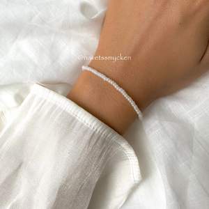 Pärlarmband av skimrande glaspärlor i vit nyans. Perfekt att kombinera med andra smycken! Armbandet är ihopsatt med hållbar elastisk tråd och passar de flesta handleder.