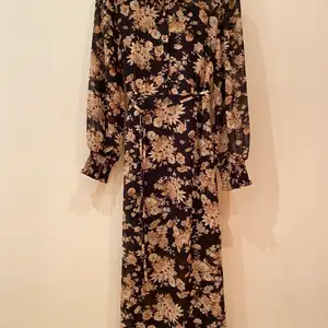 Svart/blommig klänning från Vila, använd ett fåtal gånger, svart underklänning ingår. Köparen står för frakten (62kr) 