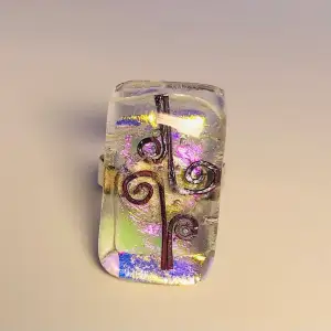 Justerbar ring i sterlingsilver och glas i grön, rosa och lila med dekoration i koppartråd. Glasets storlek är 2,8 x 1,6 cm.