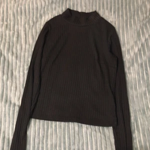 Svart ribbad polotröja stl S - Svart ribbad långärmad tröja med en liten polokrage. Tajt passform men stretchigt material.