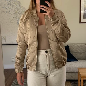 Bomberjacka med asieninspirerat mönster  - Jättefin beige/guldig bomberjacka från soaked in luxury med blommönster i orientalisk stil. Nypris ca 1000 kr