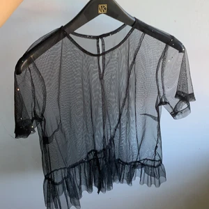 Mesh top med glitterstjärnor - En topp från okänd butik med volanger nertill. Toppen har använts vid 1 tillfälle och är i samma skick som vid köp. Den passar de flesta men jag gissar på att toppen är i en storlek medium. Den sitter löst på kroppen och är jättefin med en bralett under som exempel. 