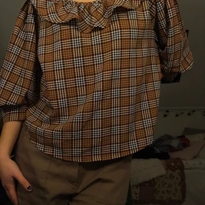 rutig blus - rutig blus från monki med volang runt halsen. Luftigt material.