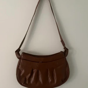 Brun axelremsväska - En brun axelremsväska. Bra skick, inga slitningar med två stora fack med dragkedjor. Mått 30cm bred och 20cm hög😊