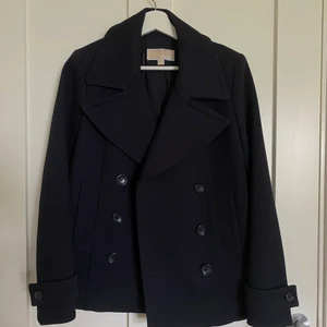 Kappa - Marinblå från Michael Kors. Storlek S. Toppskick endast kedjan man kan hänga kappan med som gått av.