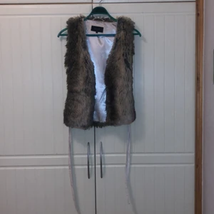 Päls väst (fake) - Jag säljer den här päls västen pga att den inte kmr t användning den är i nyskick, den e jätte fin man kan ha den över tunna jackor 