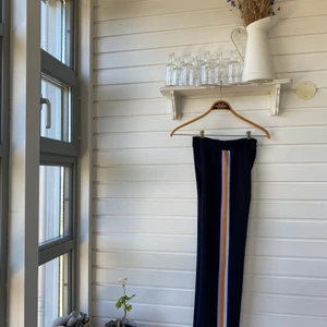 Zara, Kostymbyxa med mönster, XS - Marinblå kostymbyxa med fyra färgade ränder på sidan, från Zara. Storlek Xs. Hög i midjan, dragkedja som spänne. Har sytt upp till mig som ör 158cm