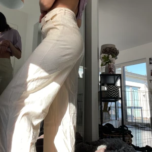 Beige tygbyxa NA-KD - ”Belted wide pants” från NA-KD. Storlek 34, sjukt snygga byxor som har ett tyg material, vida i benen och tajta med ett tyg bälte runt midjan. Beiga i färgen. .