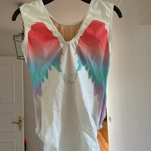 Gymnastikdräkt - Jättefin gympadräkt, använd i ca. 1 år. Storlek AXS, men passar även om man är lite större, tyget anpassar sig snabbt. En del paljetter saknas på framsidan, men det märks inte och påverkar inte kvalitén av tyget.  Snygga vingar på baksidan, aningen v ringad rygg och dubblett på framsidan. Perfekt dräkt för den som vill stå ut lite extra!!! Design av Jonna Adlerteg.