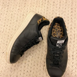 Stan smith - Stan smith i äkta läder från ADIDAS. Skon är i färgen svart med en mocka detalj i leopard mönster på bakkappan. Sulan är i vitt. Skorna har även en innersula i leopardmönster. Storleken är 36,5 men kan passa en 36a också. 