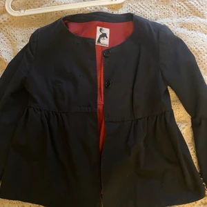 Jenny Westerlind kavaj medium - Svart med rött foder. Väldigt fin. En knapp saknas i fram med extra knapp är fäst på tvättlappen. Ngt blekt men i övrigt hel. Det finns ingen storlek angiven. Normal medium skulle jag gissa.