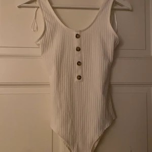 Gullig vit bosy - Super söt vit body som är oanvänd. Hade helt glömt bort denna toppen när jag plötsligt hittade den i garderoben och nu är den lite för liten. Köpte denna på hm förra året och den har som sagt lappen kvar. 