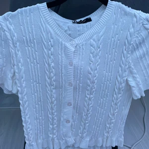 T-shirt med detaljer xs/s - T-shirten är med knappar och har väldigt fina detaljer som man kan se på bilden och volanger på slutet,passar jätte fint med lågmidjande jeans och bara använd 2 gånger