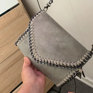 Grå axelväska - Säljer en Stella McCartney liknade väska,vid fler bilder kom privat!💓 Den är i gott skick! OPS! Ett puder gick sönder i väskan så innuti är lite smutsigt vet ej ifall d går bort!