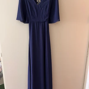 Långklänning strl XS - Långklänning i mörkblå, knyts i ryggen. Inköpt på Asos. Endast använd 1 gång på ett bröllop. Täcker fötterna på mig som är 170cm. Kommer inte till användning, köp köp! 