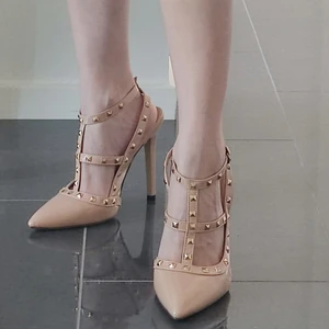 Klackskor med nitar i storlek 38 - Helt nya oanvända glansiga stilettklackar med guldiga nitar i färgen beige/ljus rosa. Höjden på klacken är ca 12,5 cm och säljs p.g.a att jag köpte dem i fel storlek. 