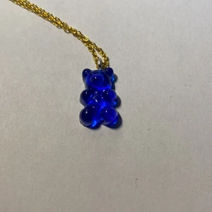 Guldigt halsband med en blå nallebjörn - Kedjan: 28,3 cm lång.  Nallen:1,5 cm lång.  Guldig kedja med en söt liten nallebjörn på.