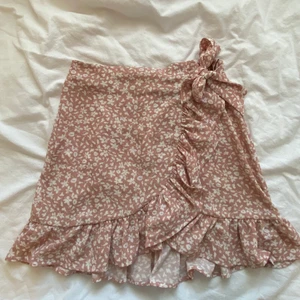 Söt rosa kjol - Säljer denna söta omlott kjolen. Ljusrosa med vita små blommor. Passar perfekt till sommaren. Finns ett band som gör att man kan justera hur man vill att den ska sitta i midjan. Använda några gånger så skicket är bra💞💞