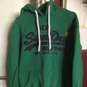 Superdry Hoodie - Hoodien är i fint skick, knappt använd. Passar perfekt om du vill ha en ”oversized” hoodie. Fin färg och trycket är inte skadat. Inköpspris: 550kr