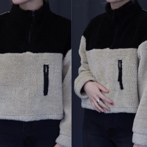 Fluffig fleece - Fluffig fleece i färgen svart och beige. Liten ficka på ena sidan och dragkedja vis halsen. Bra skick🧸