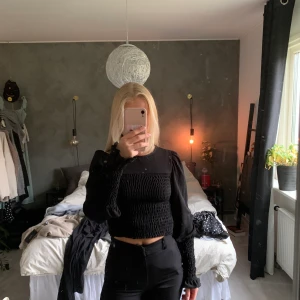Svart smockad blius från gina tricot - Jättegullig svart smockad blus från gina tricot. Jättemjukt tyg och små puffärmar. Använd 1 gång och säljer då den inte kommer till användning. 