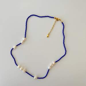 blått pärlat halsband med några fejk sötvattenspärlor😍 ett superfint halsband perfekt till alla olika tillfällen✨ knutgömman, låset och kedjan är guldpläterade (därav det högre priset). inga gröna smycken här😍✨