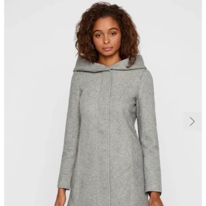 Höstkappa Vero Moda - Fin grå kappa, perfekt nu för hösten med skön huva och bra längd. Bra skick, sparsamt använd. Storlek medium  Betalning via swish, köpare betalar frakt.  Material: 85% Polyester, 15% Bomull Längd:82cm