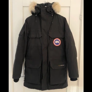 Canada Goose Expedition Parka - svart - Säljer en jätteskön tjock dunjacka: Canada Goose Expedition Parka i svart (modell 4565M R). Äkta - köpt på NK i Stockholm. Unisexmodell. Storlek 2 XS men passar bra på mig som är 177 cm. Perfekt för vintern! Nypris ca 16 000 kr. Den är i mycket bra skick. Mudden på ena ärmen är lagad efter att tyget repat upp sig lite men det är inget som syns. Det är en jättefin jacka. Jag säljer jackan för att jag har köpt en ny. Köparen står för frakten❤️