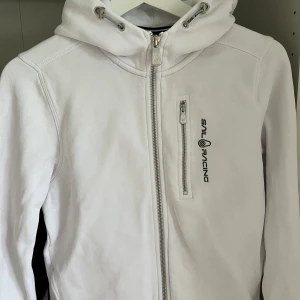 SAIL RACING ZIP HOODIE VIT Storlek 160 - Växte ur tröjan snabbt så han inte använda den så mycket. Skick 9/10. nypris 1 000 kr. Storlek 160 men passar ävem större. Kan mötas upp i Göteborg.kan frakta men köparen står för frakt.