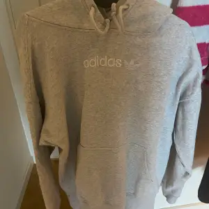 En grå adidas hoodie som är i storleken xs men är oversized så den sitter som en M ungefär.