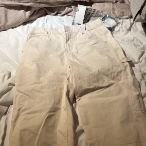 Bershka - Gräddvita snickarjeans - Oanvända byxor säljes eftersom jag glömde skicka tillbaka dem och de är för stora för mig. Det är storlek EU 44 snickarjeans, mycket snygga. Gräddvit färg  Bara några veckor gamla och aldrig använda.
