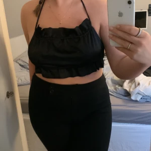 Svart satin topp - Svart satin topp som är öppen i ryggen, man knyter toppen i ryggen med snören, lite kort för mig då bysten blir för stor för toppen så skulle säga att den passar S!