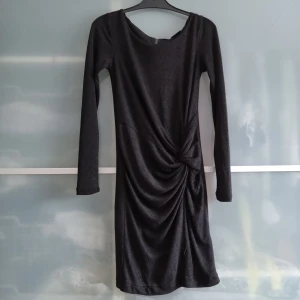 Festklänning  - Svart klänning från Vila med glittrigt inslag i tyget. Använd fåtal gånger. Jätteskön på och sitter väldigt fint. Passar perfekt för fest!