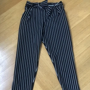 Kostymbyxor svart- vitrandiga - Kostymbyxor med (skärp) knyte i midjan. Svart- vitrandiga. Oanvända!