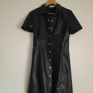 Skinnklänning mango - Klänning i skinn-imitation från Mango. Knäppning hela vägen. Mycket gott skick.