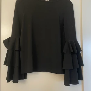 Blus - Svart blus med volang ärmar