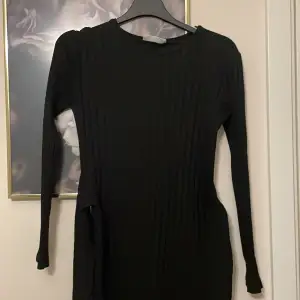 lång svart klänning med en slits på sidan
