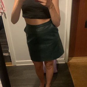 Grön läderkjol - Grön läderkjol (fejk). Knappt använd. Blixtkedja där bak, fickor på sidorna. 