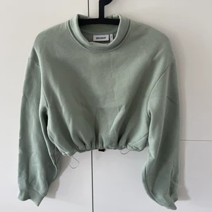 Tröja, Weekday - En fin grön lite halv croppad tröja från Weekday med justerbara midja. På bilden är kragen nervikt men kan även vara polo. Använd fåtal gånger.