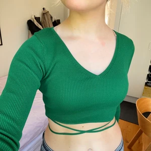 Grön topp - Grön ribbad crop top från Zara med knytband som man kan knyta på olika sätt. Strl M men liten i storlek. Slutsåld på hemsidan, aldrig använd