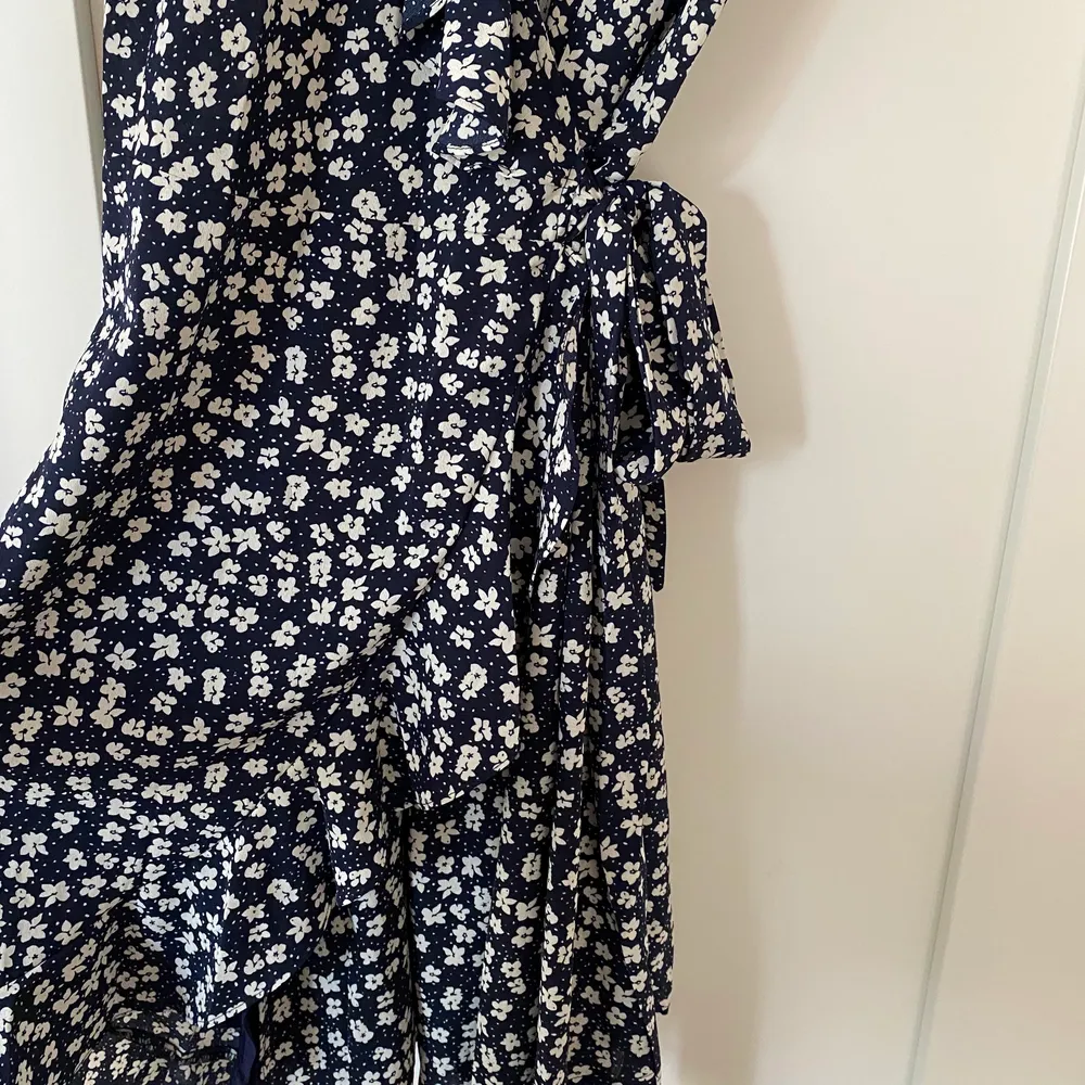 Säljer denna marinblå och blommiga omlottklänning. Inköpt på Smögen förra sommaren (2021) för 399kr. Aldrig använd och i fint skick! . Klänningar.