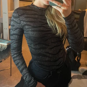 Partytopp strl S - Randig partytopp i glitter och svart, med öppen rygg. Strl S.