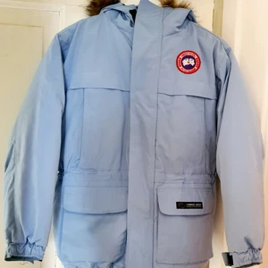 Canada Goose  - Canada Goose jacka (ej äkta) i fin ljusblå färg med äkta päls på huvan. Jättetjock och varm jacka i mycket bra skick. Storlek junior XL, motsvarar ca S, ev M för dam.