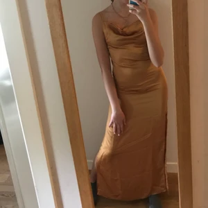 Guldig balklänning strl 34 - Skimmrig, guld/brons liknande färg på balklänningen som är i strl 34! Den är i gott skick eftersom den endast har använts en gång på en bal 2019! Lätt i tyget och faller fint på kroppen! 
