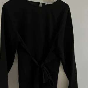 Blus med knytning - Svart blus med knytning i midjan som framhäver formen. Super söt! 