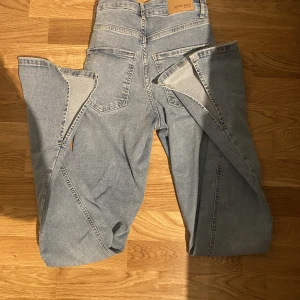 Ljusblåa jeans med slitt - Otroligt snygga ljusblåa jeans med slitt och av väldigt skönt material som sitter snyggt och formar kroppen. Aldrig använda köpa på gina tricot. Sitter perfekt vid magen. Tidigare pris 599kr