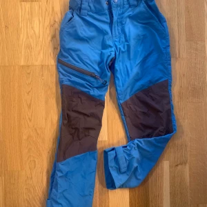 Vandringsbyxor i stretch stl 128 - Knappt använda. Blå byxor för utomhus. Stretchmaterial och förstärkning på knän. Vattenavvisande. Perfekt för fjällvandring. Stl 128. Neomondo. Säljer även en jacka från Didricksons i liknande färg. Se mina andra annonser. 