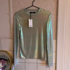 Silvrig tröja  - Silvrig/skimrande tröja. Aldrig använd så prislappen är kvar. Frakten inräknad i priset. Skriv vid frågor!