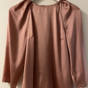 Blus - Blus i glansigt material, slutar precis nedanför bilden. Aldrig använd. (+ Frakt) 🤗